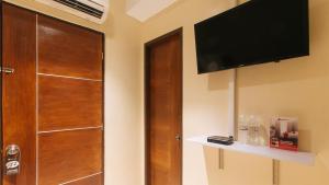 圣胡安RedDooorz @ Laiya Vivo Hotel Batangas的客房设有木门和平面电视。