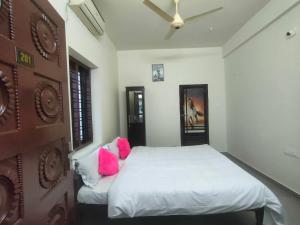 PonnāniJinnens Tourist Home的卧室配有白色床和粉红色枕头