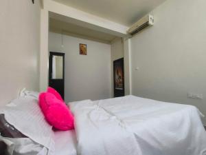 PonnāniJinnens Tourist Home的一张白色的床,上面有粉红色的枕头