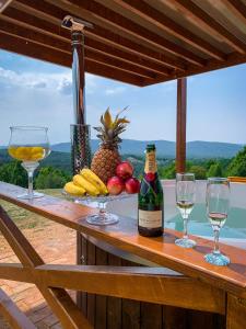 克拉多沃Vila Promaja的一张桌子,上面放着眼镜,还有一瓶葡萄酒和水果
