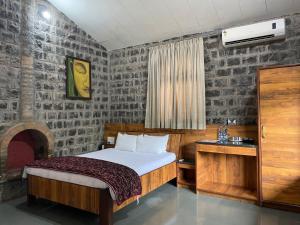 浦那The Green Gate Resort Mulshi的一间卧室配有一张床、一张桌子和一张四柱床。