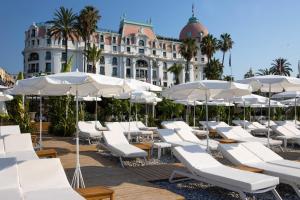 尼斯Hotel Le Negresco的大楼前的一堆白色椅子和遮阳伞