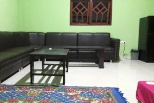 比拉Penginapan asidik的客厅配有黑色沙发和桌子