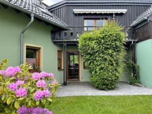 蒙绍Behagliches Haus mit Kamin的院子里的绿色房子,有粉红色的花