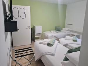 卢布尔雅那AZUR ROOMS LJUBLJANA的一间设有四张床铺和白色床单的客房