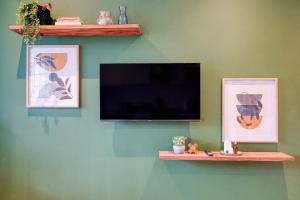 德班Hampton Collection - Charming 1 or 2 Bedroom Apartment with Pool的绿色墙上的平面电视,两幅照片