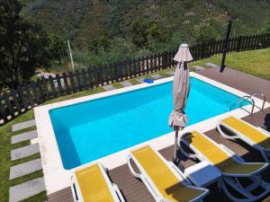维埃拉·多米尼奥Quinta da Resteva-Chalé do RIBEIRO的一个带躺椅和遮阳伞的游泳池以及游泳池