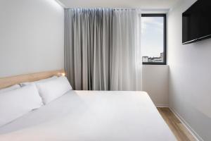 维拉诺瓦-德法马利B&B HOTEL Famalicão的卧室配有白色的床和窗户。