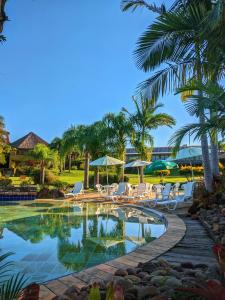 维亚芒Vila Ventura Ecoresort的度假村的游泳池,配有椅子和遮阳伞