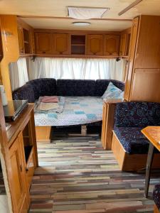 希典SEA CARAVAN ON THE BEACH的小房间,配有沙发和一张位于走廊的床铺