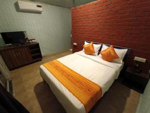 塞恩Tamboo Resort Vajreshwari的一间卧室设有一张带红砖墙的大床