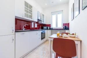布达佩斯Corvinus Smart Apartment with Beautiful View的红色和白色的厨房配有桌椅
