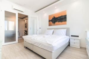 布达佩斯Corvinus Smart Apartment with Beautiful View的白色的卧室设有一张大床和一间浴室。
