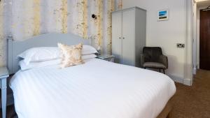 珀斯阳光水岸大厦地铁酒店的卧室配有白色的床和椅子