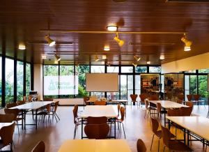 伊东ISOLA Izukogen的一间带桌椅和屏幕的用餐室