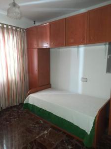 Piso en Montillana的小房间设有一张床和木制橱柜