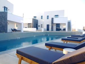 莫诺利索斯myLithos Suites的一座带蓝色软垫椅子的游泳池,位于一座建筑旁边