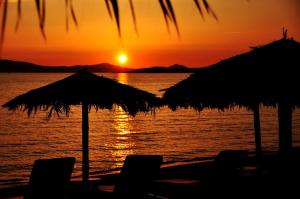 圣安娜纳克索斯Sunday Luxury Suites的海滩上的日落,配有椅子和遮阳伞