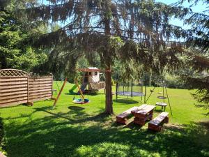 PodwilkNoclegi nad Czarną Orawą的公园内设有一个游乐场,配有野餐桌和一棵树