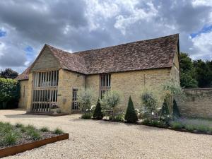 Great Milton17th Century Barn near Le Manoir aux Quat’Saisons的一座大型石头建筑,设有大屋顶