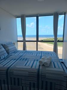 累西腓FLAT BEIRA MAR BARRA DE JANGADA RECIFE ANDAR ALTO的一间卧室配有一张床,享有海滩美景
