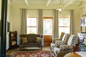 克拉伦斯Baris Guesthouse的客厅配有两把椅子和两扇窗户