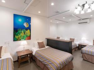 冲绳岛市科扎酒店的一间设有三张床的客房,墙上挂着一幅画