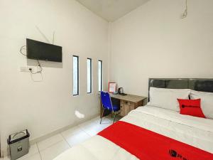马塔兰RedDoorz Syariah near Siloam Hospital Mataram的一间卧室配有一张床、一张书桌和一台电视。