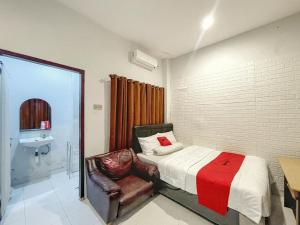 马塔兰RedDoorz Syariah near Siloam Hospital Mataram的一间卧室配有一张床、一把椅子和一个水槽