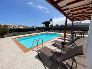 普拉亚布兰卡Villalia Capri的一个带椅子和桌子的游泳池