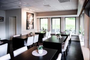 FiskåMoens Motell的餐厅设有黑桌和白色椅子及窗户。