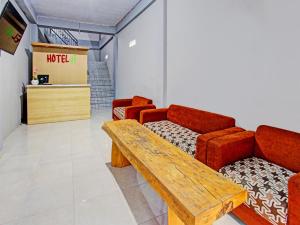 萨萨克OYO 91210 Hotel J3的一间设有红色椅子和木桌的等候室