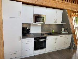 HemmoorTHE KREIDESEE 47 - Hemmoor的厨房配有白色橱柜和炉灶烤箱。