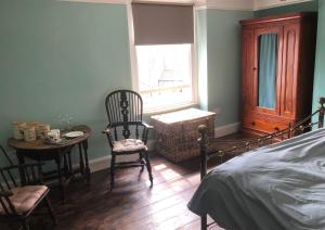 布里德波特The Victorian House的卧室配有一张床和一张桌子及椅子