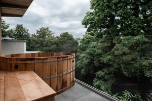 阿什伯恩Stables Ashbourne的阳台设有木浴缸和树木