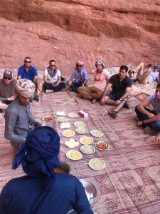 亚喀巴Bedouins life camp的一群坐在地面上吃食物的人
