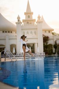 锡德Sentido Kamelya Selin Luxury Resort & SPA的女人站在游泳池边