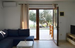 布德瓦Eco Village Buljarica的客厅设有蓝色的沙发和滑动玻璃门