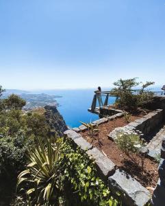 丰沙尔Getaway to Blue Paradise at Madeira Island的坐在悬崖顶上俯瞰大海的人