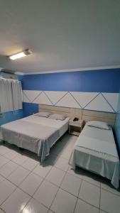 Paulo AfonsoHotel Porthal da Ilha- Paulo Afonso-Ba的一间卧室设有两张床和蓝色的墙壁