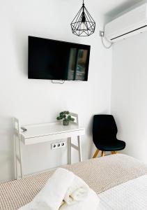 卡沃内拉斯Hostal Las Palmas的一间卧室配有一张桌子和一台墙上的电视。