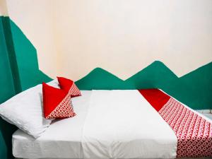 JodohSPOT ON 91512 Siantan Anambas Syariah的一张带红色和白色枕头的床