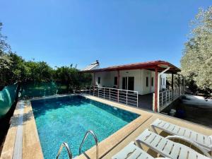 费特希耶Avci Villa-Fethiye 3+1 in Garden with Private Pool, 10 minutes to the beach的一个带椅子的游泳池以及一座房子