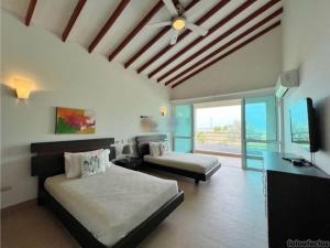 卡塔赫纳Casa Arcoíris: Espectacular casa en Cartagena con Acceso directo a la Playa的一间卧室配有两张床和一台平面电视