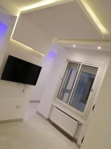 突尼斯Derby de Cité el Khadra的白色的客房设有电视和窗户。