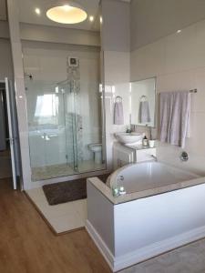 开普敦Beachfront 3-bedroom with Robben Island views的带浴缸、淋浴和盥洗盆的浴室
