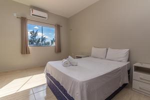 普雷亚Praieiro pousada的一间卧室配有一张带白色床单的床和一扇窗户。