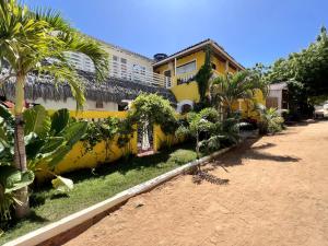 杰里科科拉Pousada Duna Beach的棕榈树前方的黄色房子