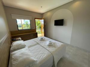 Bela Vista de GoiásHotel do Lago的卧室配有白色的床,墙上配有电视