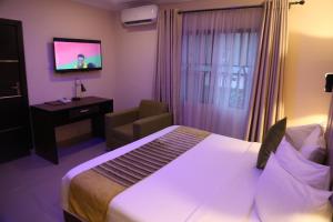 伊凯贾CLASS COTTAGE的酒店客房配有一张床、一把椅子和一台电视。